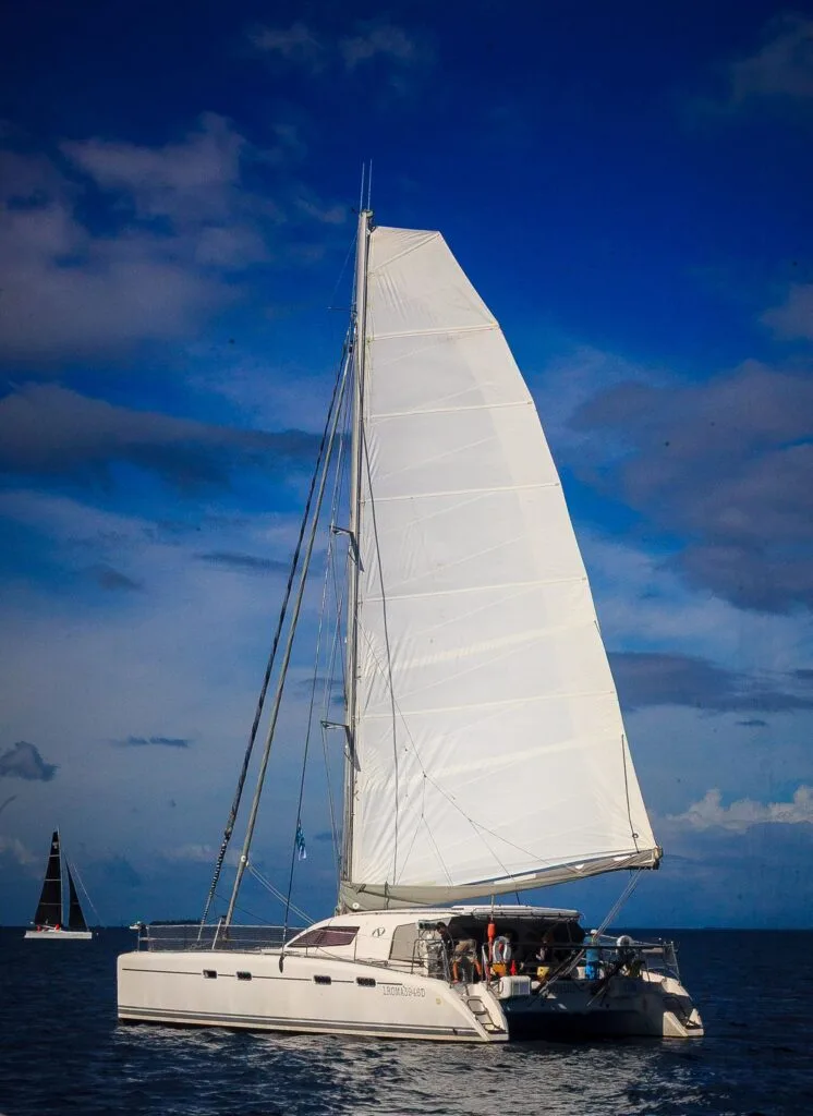 a White Sailing Catamaran with Tall Sails on Calm Blue Water, Crew Visible on Deck Under a Clear Sky. Tcupimg_3093-2026 Tcupimg 3093 2026 Régate La T cup Fête Ses 40 Ans